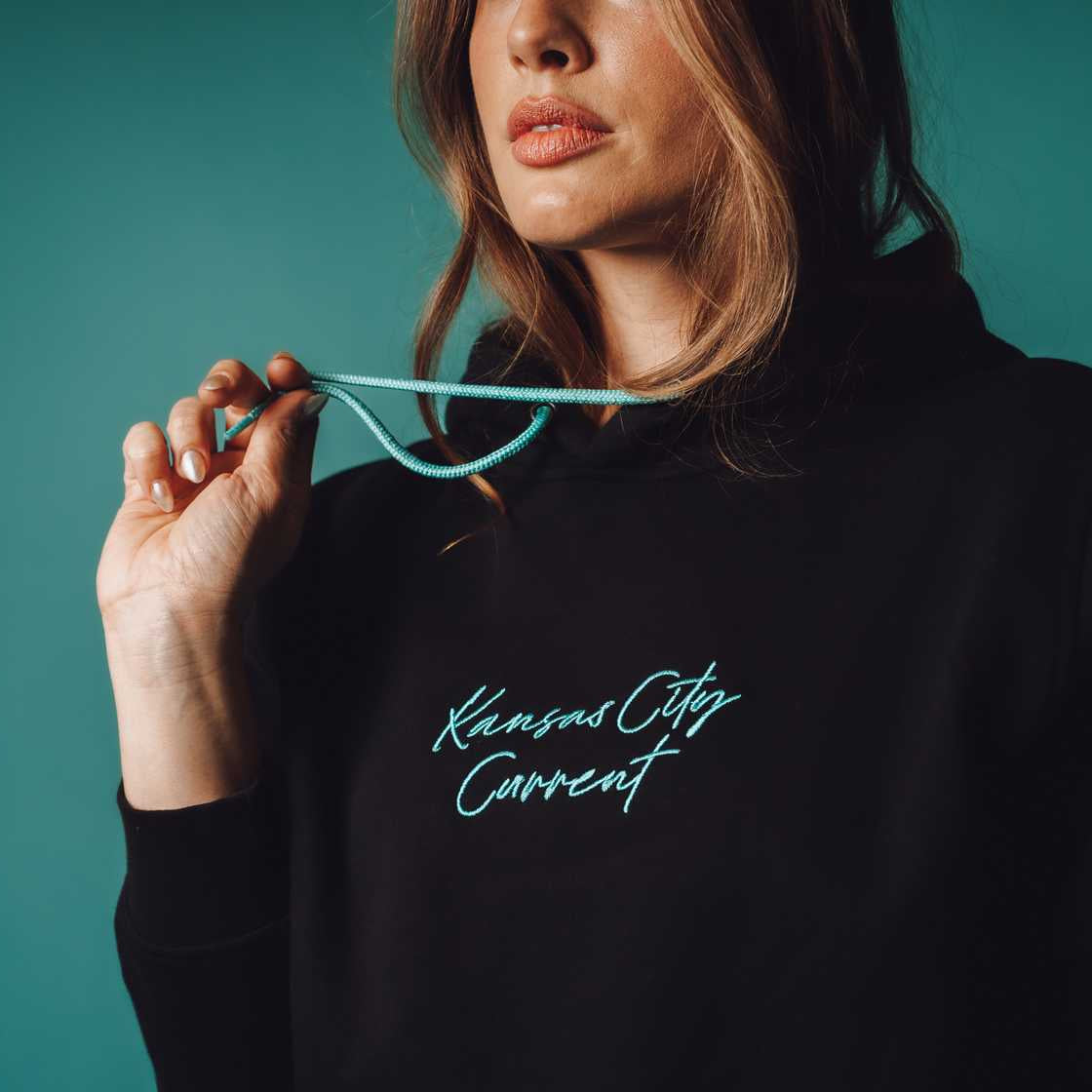 Unisex Black Teal Script Hoodie Zoomed In on Model